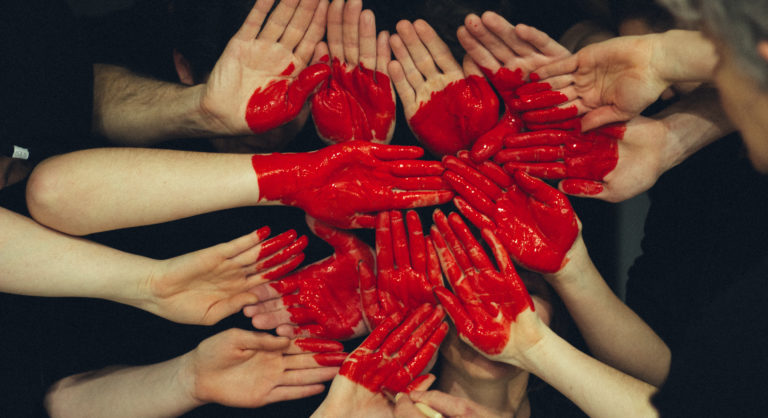 Zdjęcie serca utworzonego z pomalowanych na czerwono dłoni