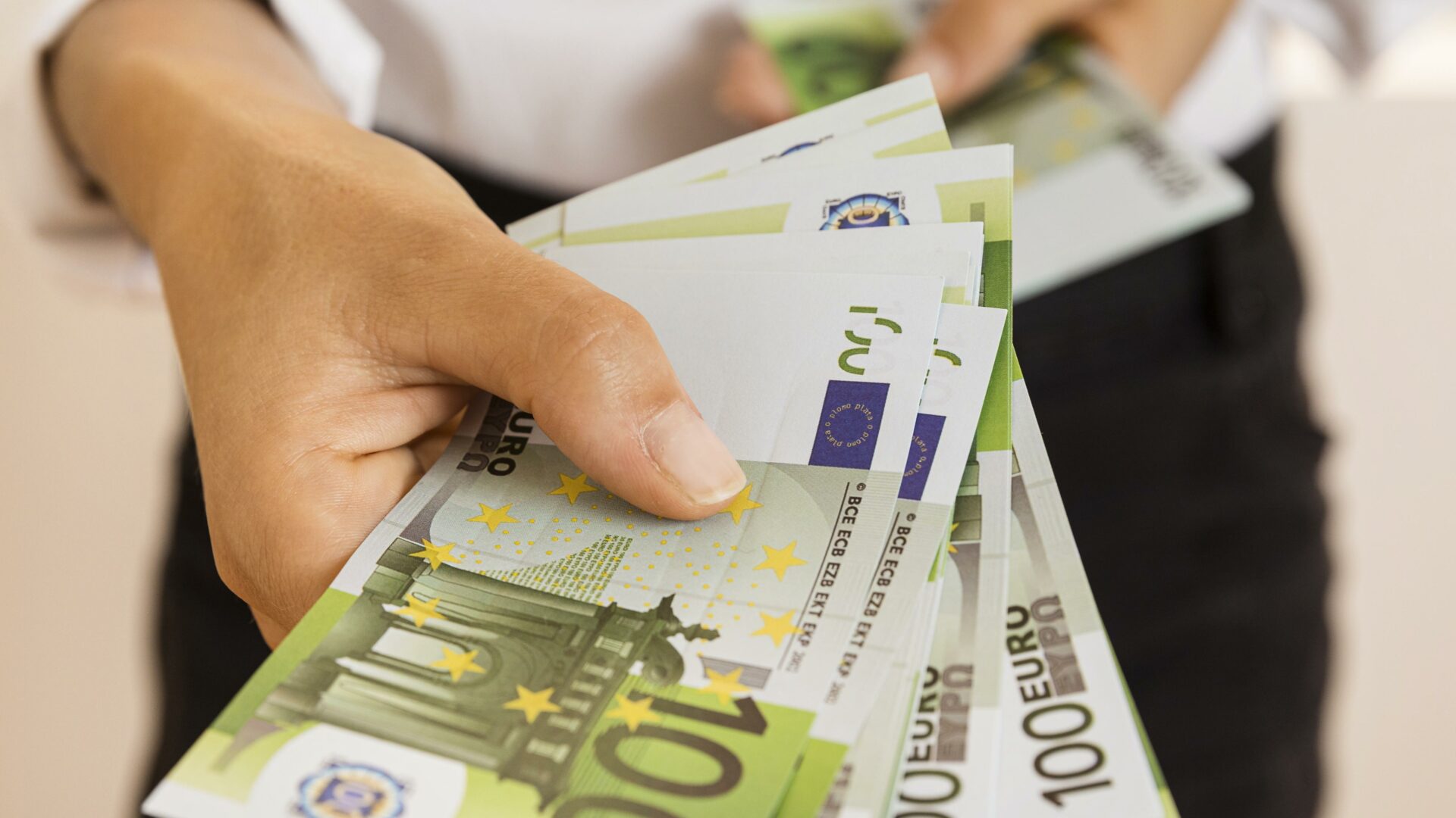 Zdjęcie przedstawia banknoty trzymane w dłoni.
