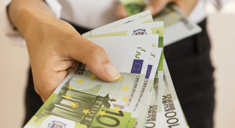 Zdjęcie przedstawia banknoty trzymane w dłoni.